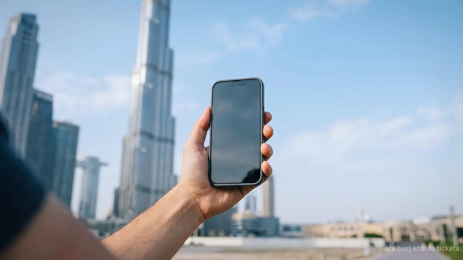 A smartphone held in hand in front of the blurred Burj Khalifa, screen blank (generated illustration)